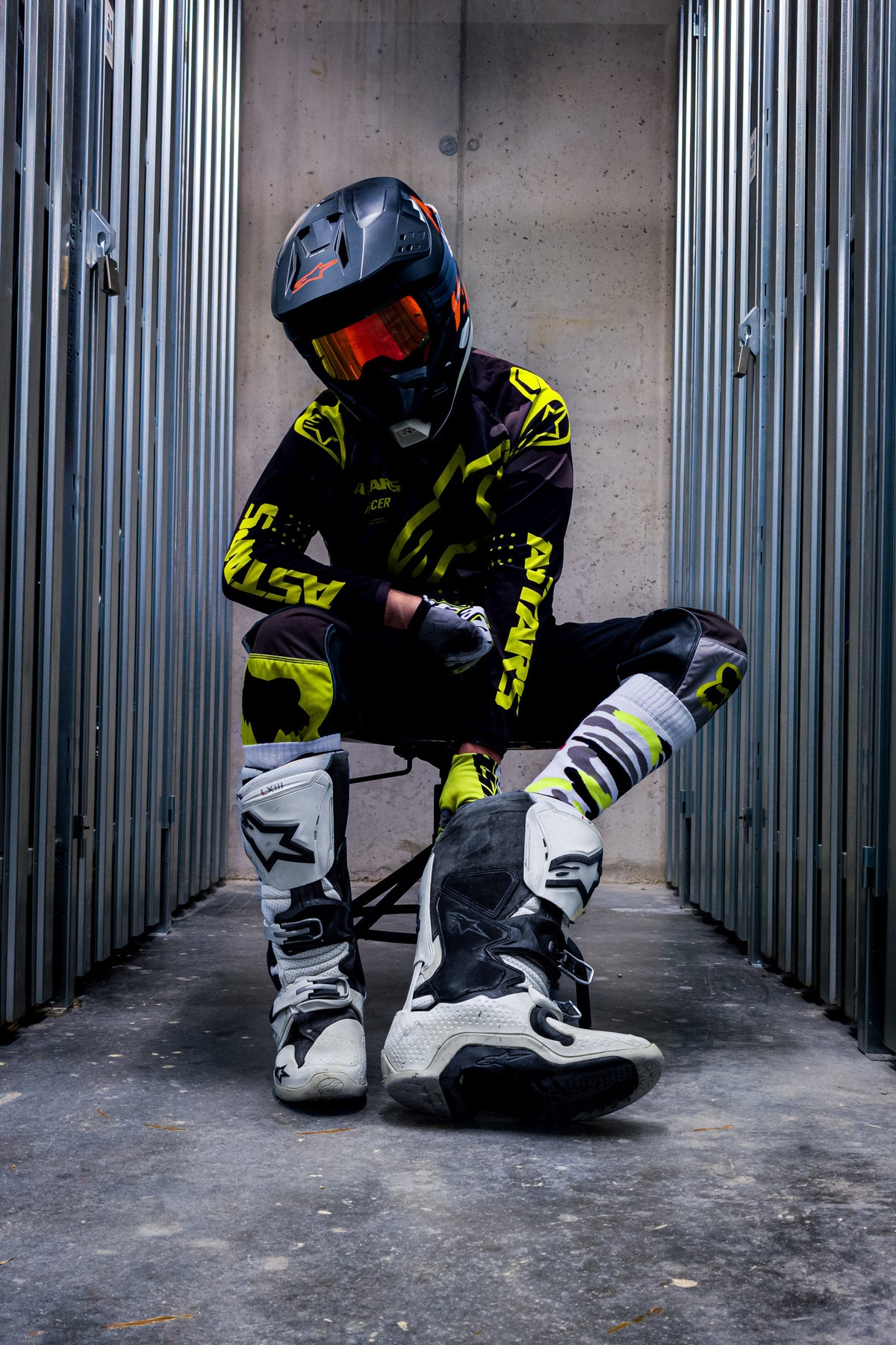 motocross biker in neon yellow dress with cross boots and MX socks in neon yellow by sk8erboy, front view, sitting in the boots