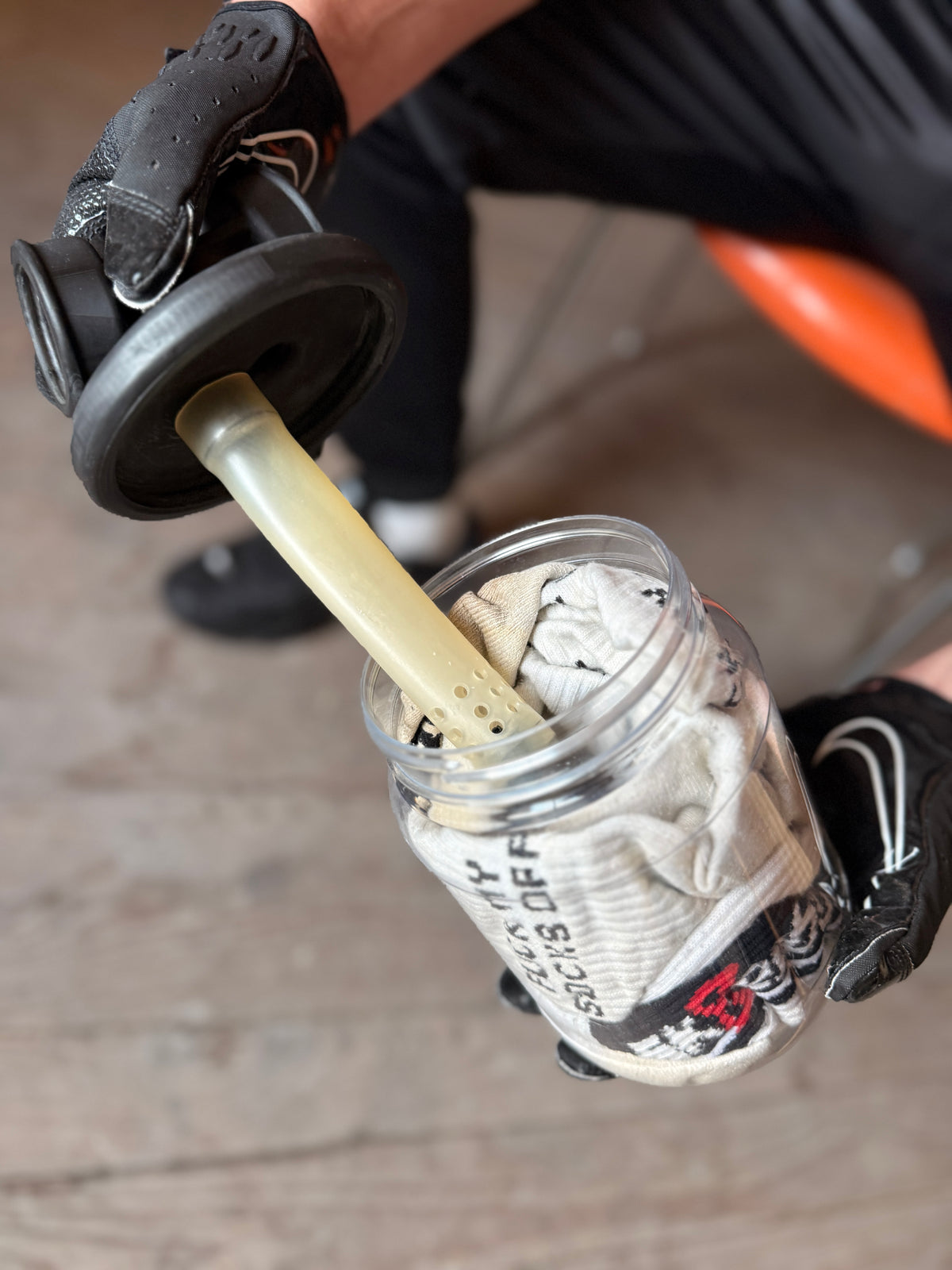 Sk8erboy Vast Sniffer glass is being opened, black gloves hold the lid with filter insert over the stuffed socks.
