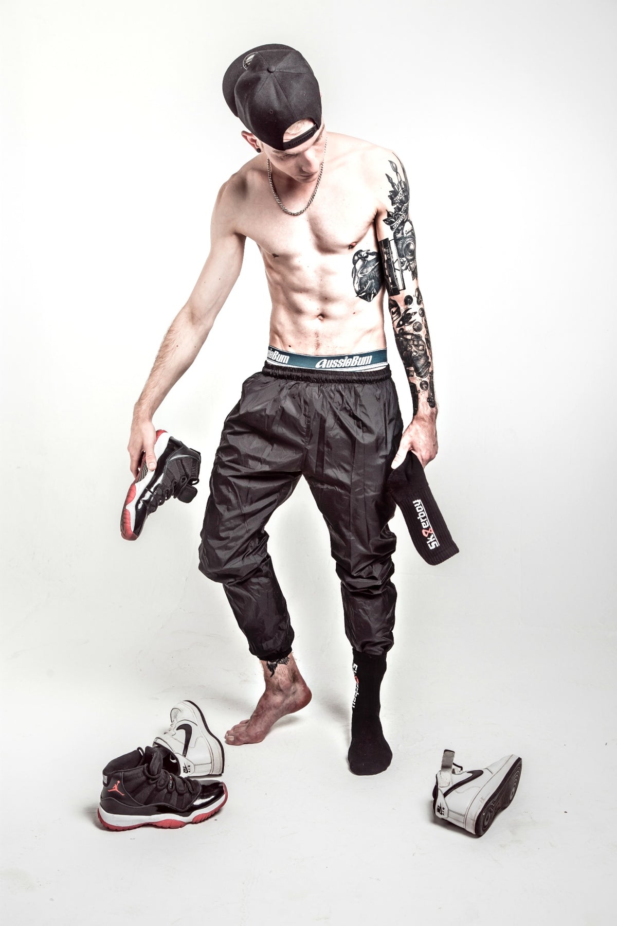 sportlicher junge mit tattoo am arm trägt eine schwarze sporthose und passende crew socks in schwarz von sk8erboy mit seinen nike sneaker von jordan