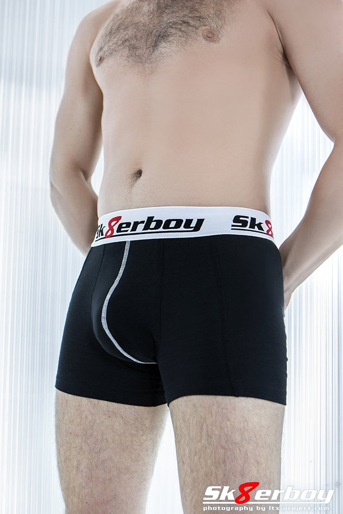 Jeune homme portant un boxer noir Sk8erboy avec ceinture blanche et grand logo Sk8erboy.
