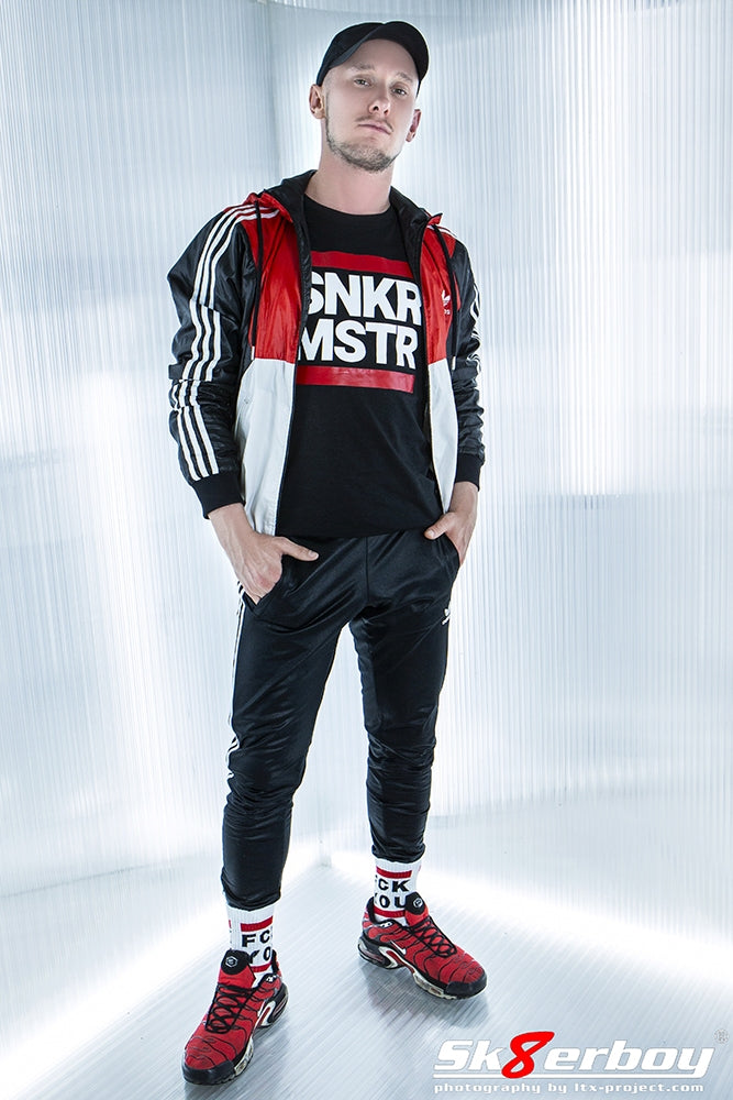 junge mit adidas trainingsjacke und hose traegt ein snkr mstr t-shirt und fck you socks von sk8erboy zu seinen roten nike tn sneaker