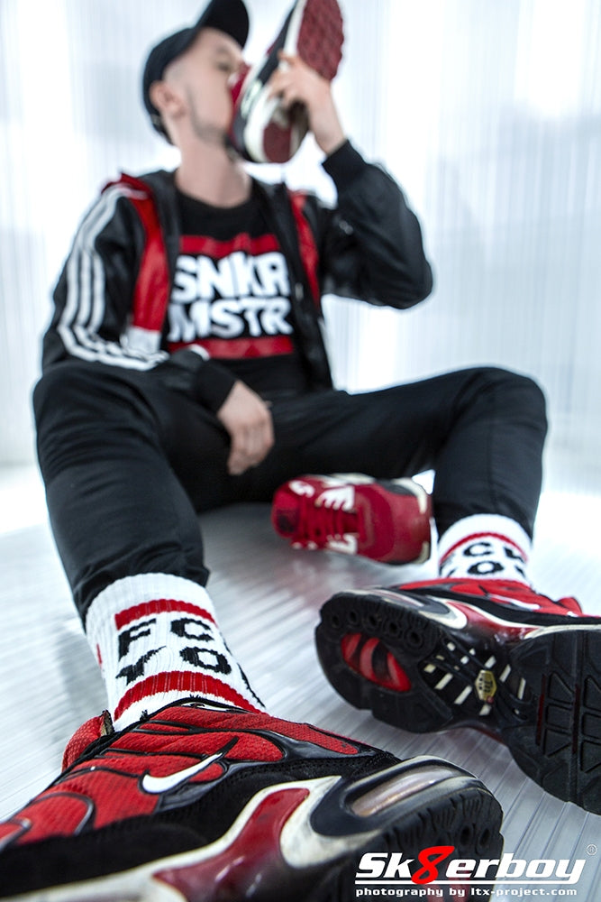 junger gay snifft an seinen sneaker und traegt sportklamotten von adidas mit fck you socks von sk8erboy und passendem snkr mstr t-shirt