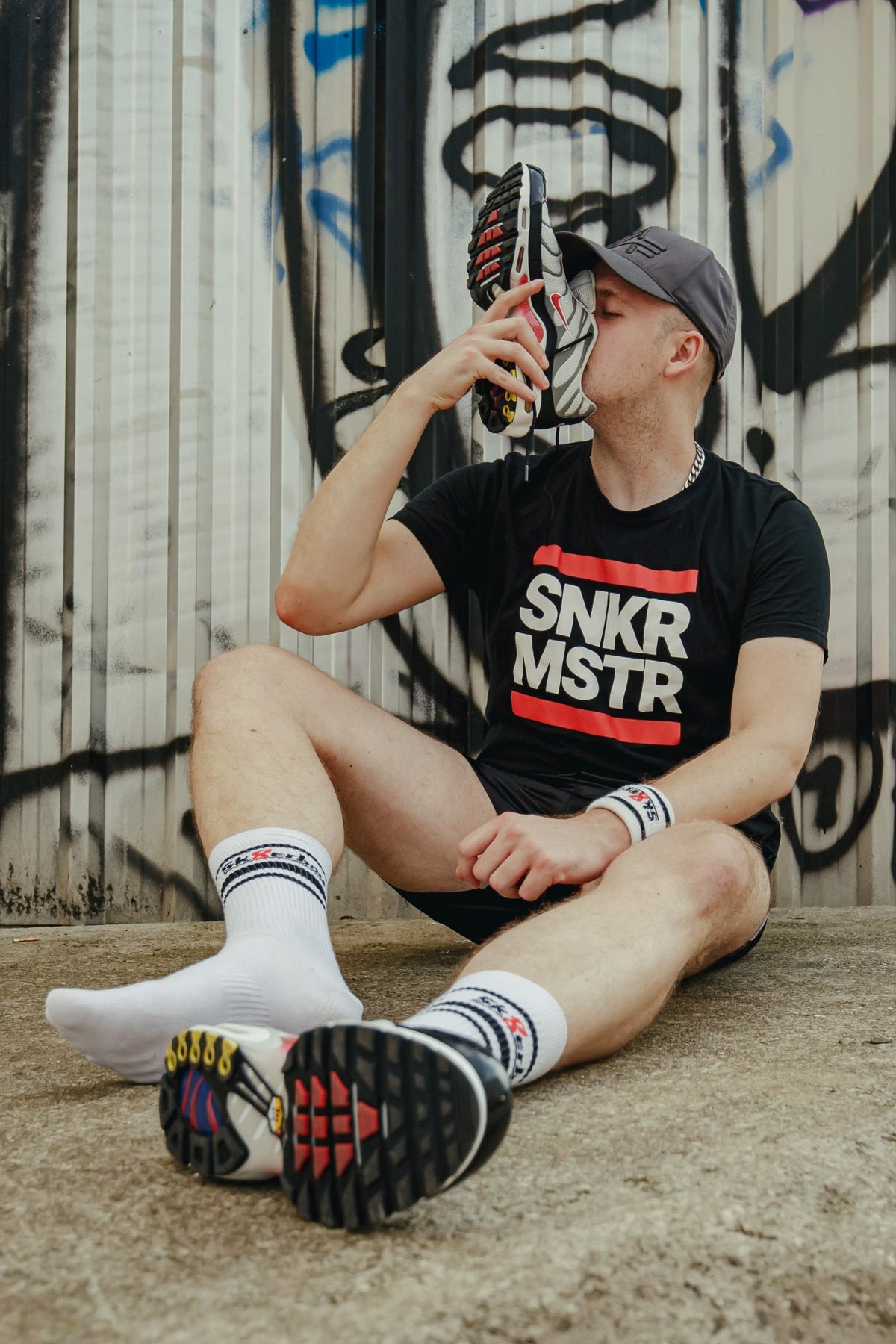 sk8erboy victory chaussettes extra fines, de qualité reconnue, particulièrement légères et idéales pour l’été, en blanc, portées par un jeune gay qui renifle ses sneakers Nike TN et est assis par terre