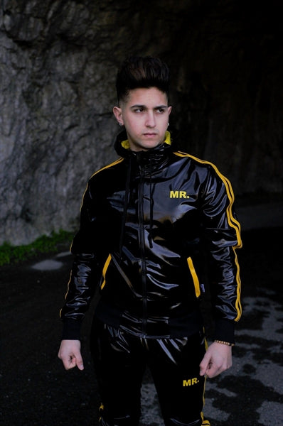 MR Riegillio PVC Tracksuit Hose mit gelben streifen von einem jungen gay getragen in schwarz glänzend mit weissen nike tn sneakern von vorne