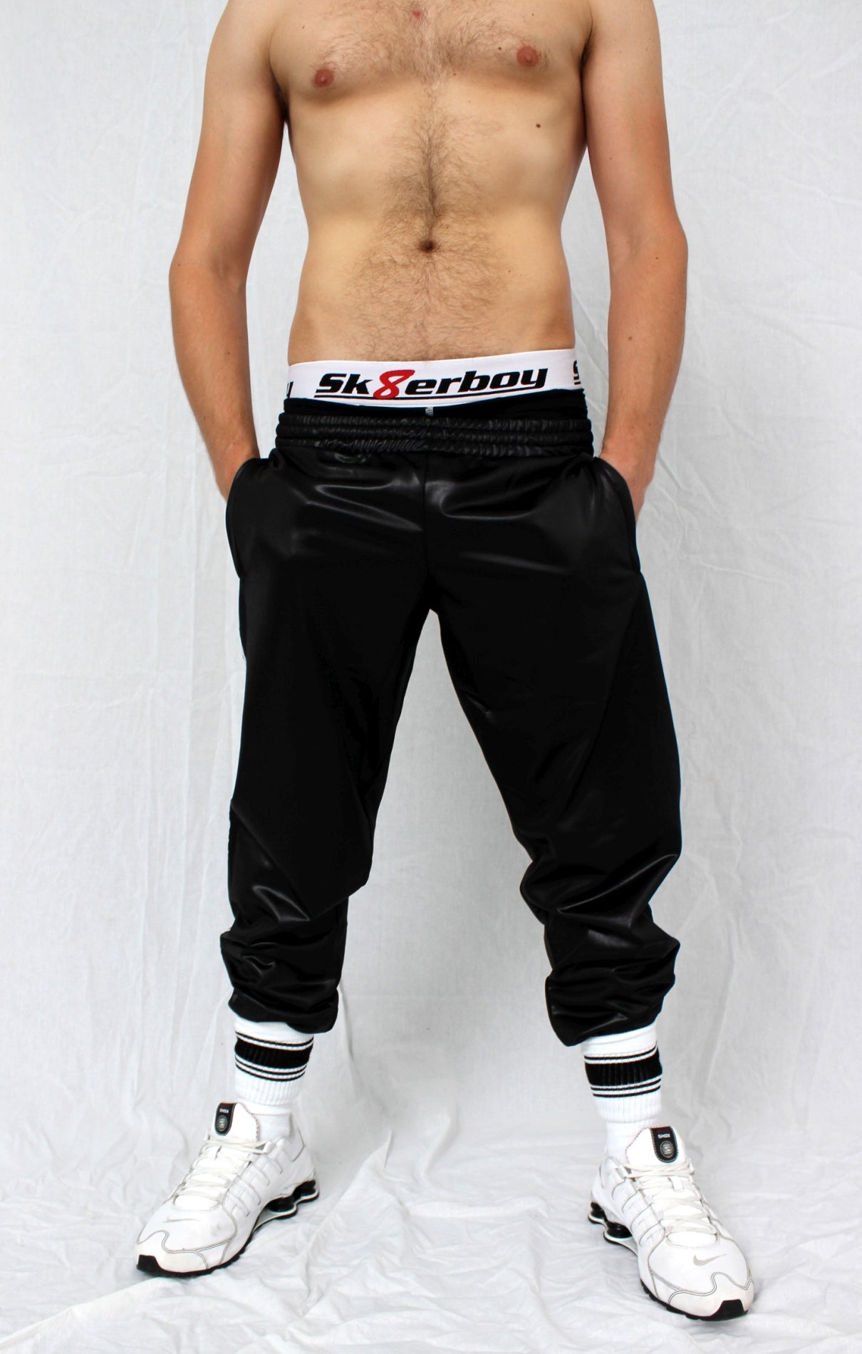 sportlicher junge trägt eine glanz sporthose und eine schwarze boxershort darunter von der der weisse bund mit großem sk8erboy logo heraus schaut in nike shox sneaker und sk8erboy deluxe socken