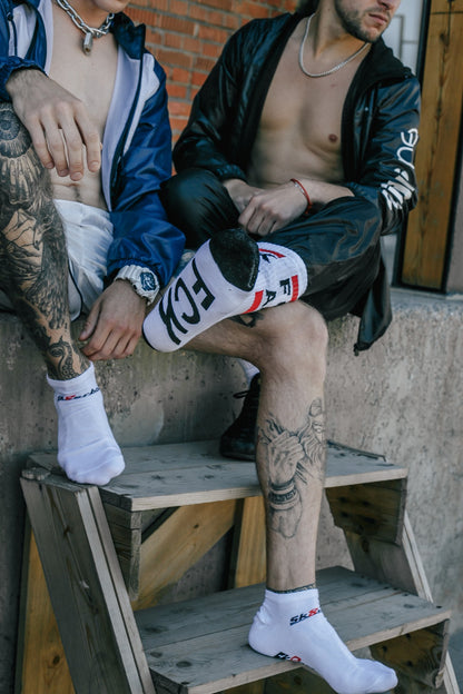 zwei gays auf einer mauer mit fck abl und sneaker socks in weiss von sk8erboy tragen sportklamotten und halskette