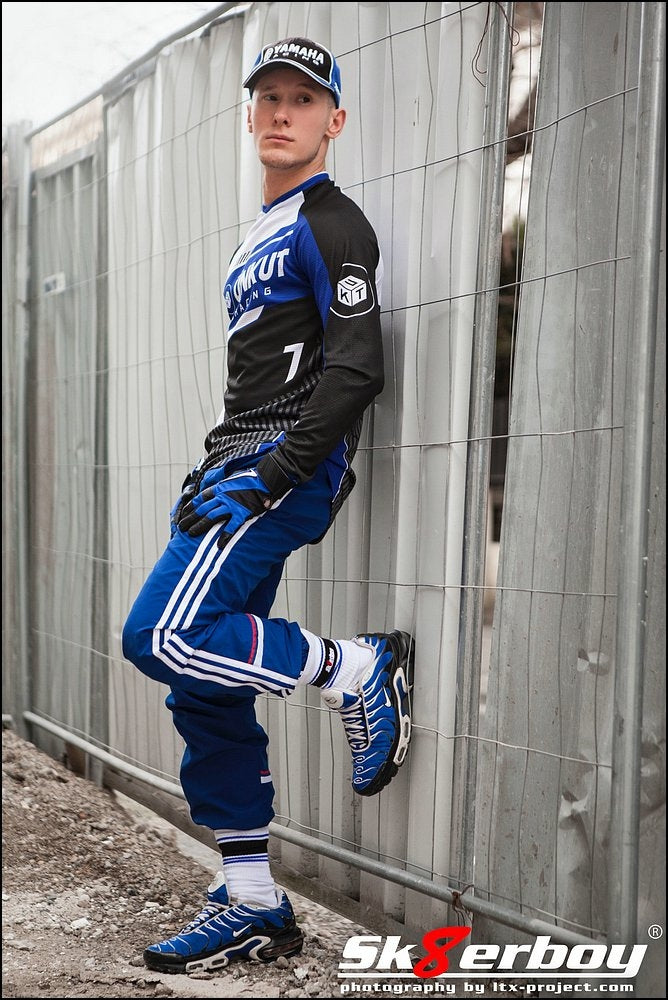 sportlicher typ lehnt an einem bauzaun mit kappe und handschuhen mit blauen nike tn sneaker dazu passende sk8erboy deluxe socks von sk8erboy socken